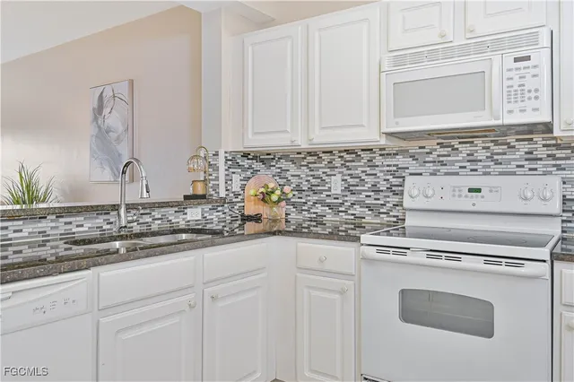 a kitchen with granite countertop white cabinets and white appliances