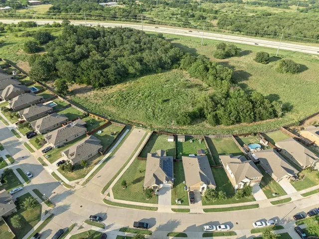 an aerial view of residential houses with outdoor space and trees