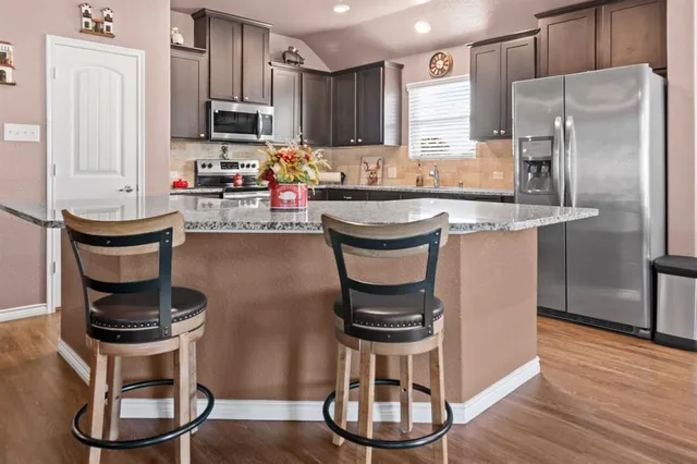 a kitchen with refrigerator a stove a sink and chairs