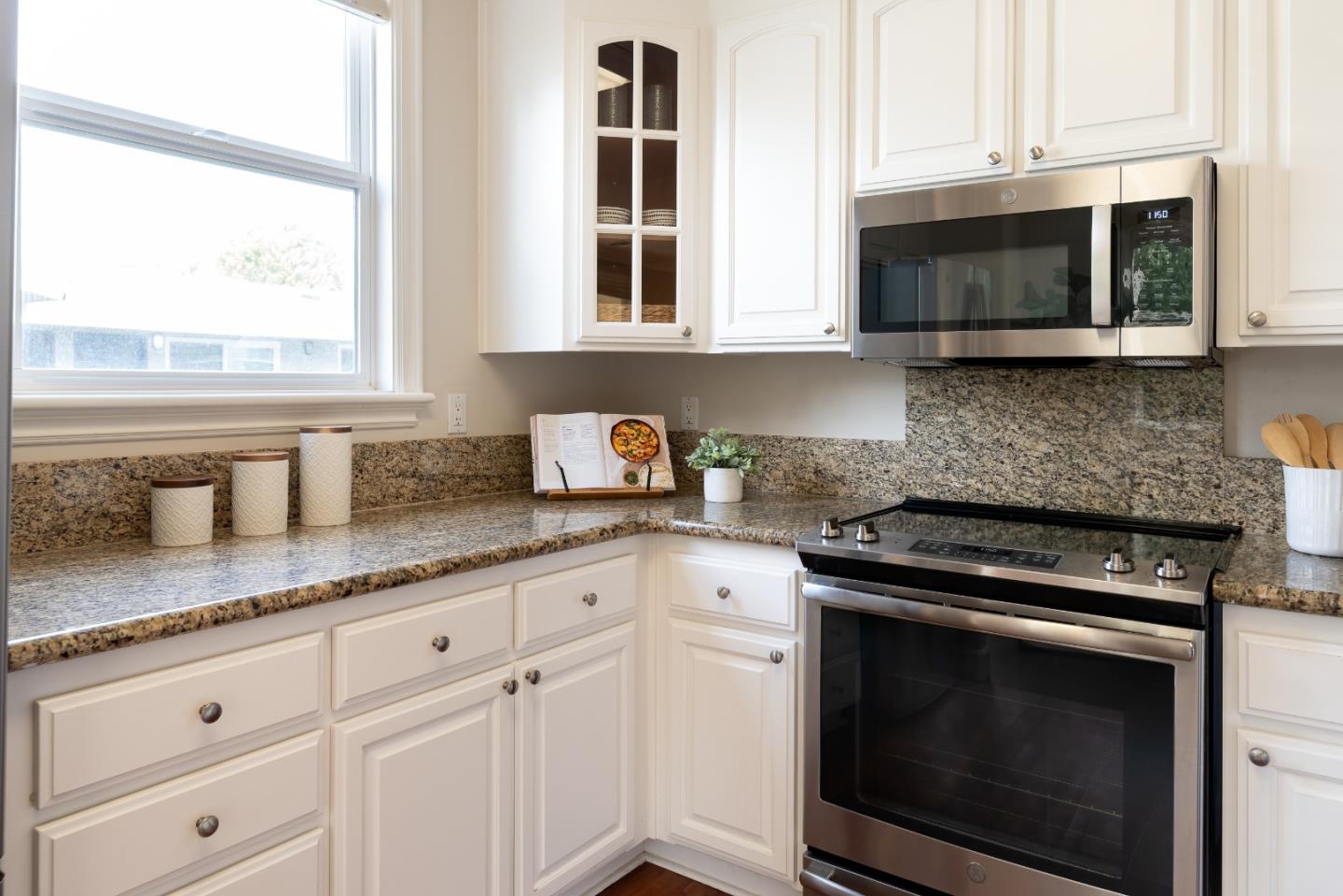 1237 Capuchino Avenue, Unit 7 Burlingame, CA 94010 - Photo 12 of 40 a kitchen with granite countertop white cabinets appliances and a window