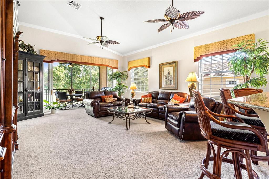 26142 Avenida Las Colinas, Unit 2B Howey-in-the-Hills, FL 34737 - Photo 16 of 78 a living room with furniture ceiling fan and a floor to ceiling window