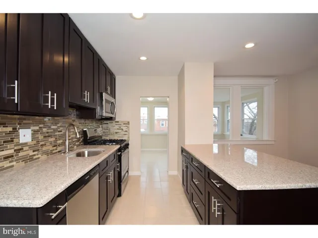 a kitchen with kitchen island granite countertop a sink stove and cabinets