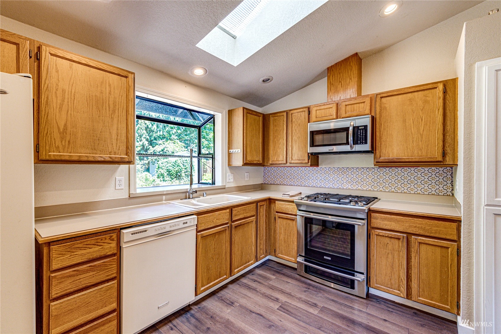 1027 233rd Place Southwest Bothell, WA 98021 - Photo 7 of 27 a kitchen with stainless steel appliances granite countertop wooden cabinets a sink and a stove