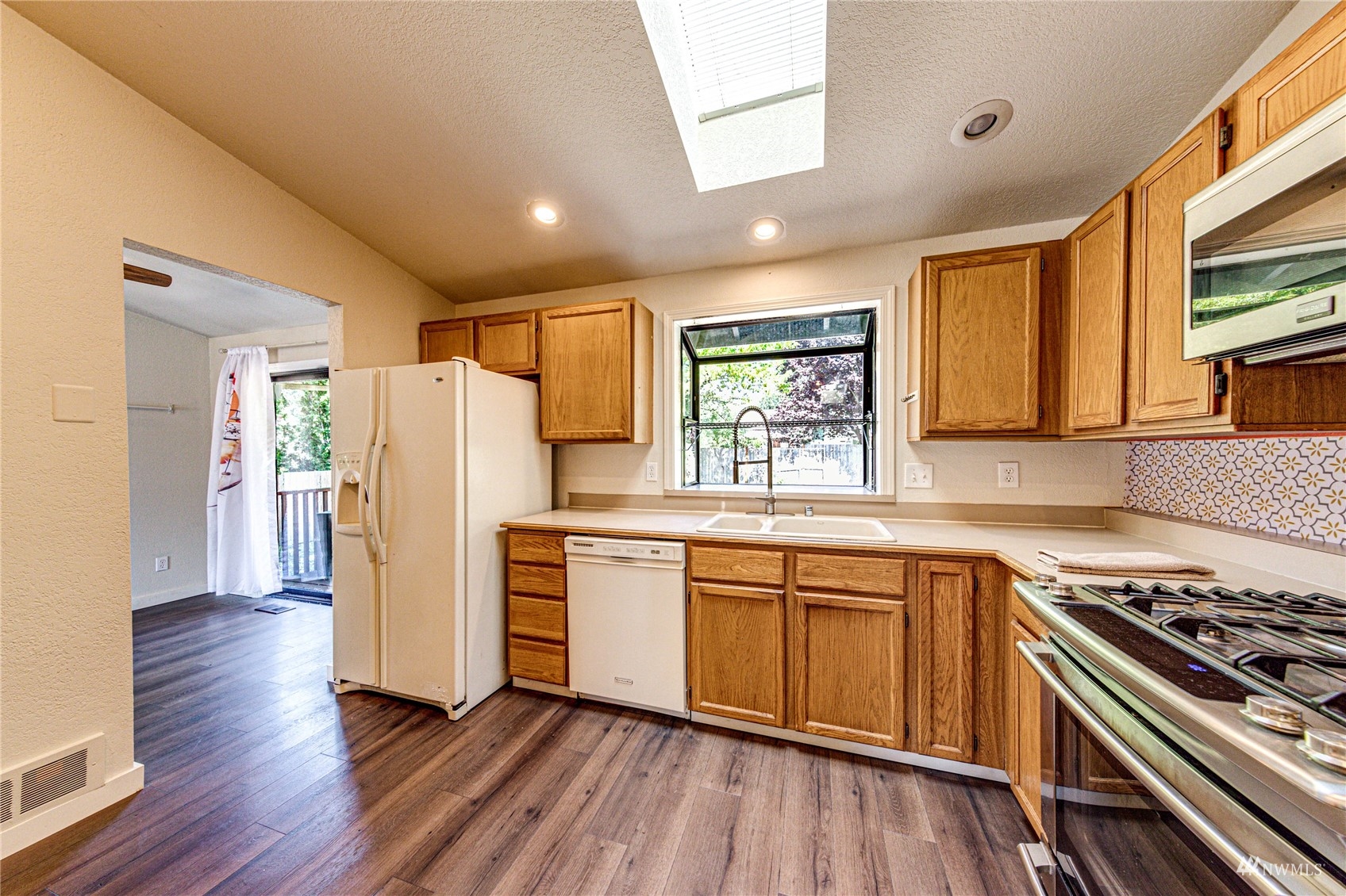 1027 233rd Place Southwest Bothell, WA 98021 - Photo 8 of 27 a kitchen with a refrigerator a sink and wooden floor