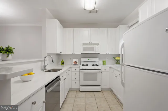 a kitchen with a sink a stove a refrigerator and white cabinets