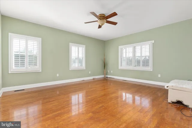 a view of room with hardwood floor and a ceiling fan