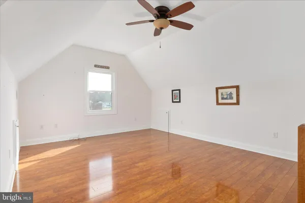 an empty room with wooden floor ceiling fan and windows