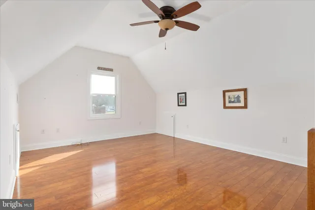 an empty room with wooden floor ceiling fan and windows