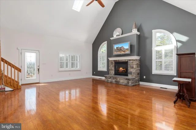 a view of an empty room with wooden floor fireplace and a window