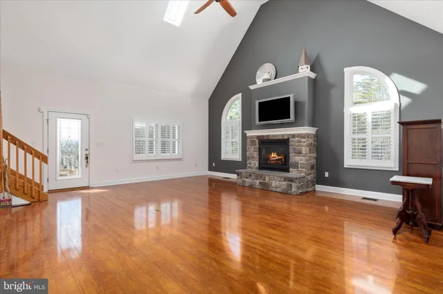 a view of an empty room with wooden floor fireplace and a window