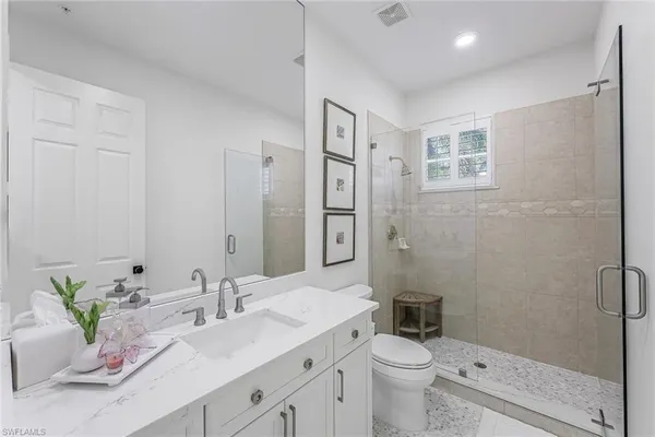 a bathroom with a granite countertop sink a toilet and shower