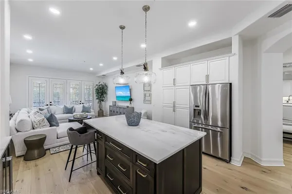 a kitchen with stainless steel appliances kitchen island granite countertop a refrigerator a sink dishwasher a dining table and chairs with wooden floor