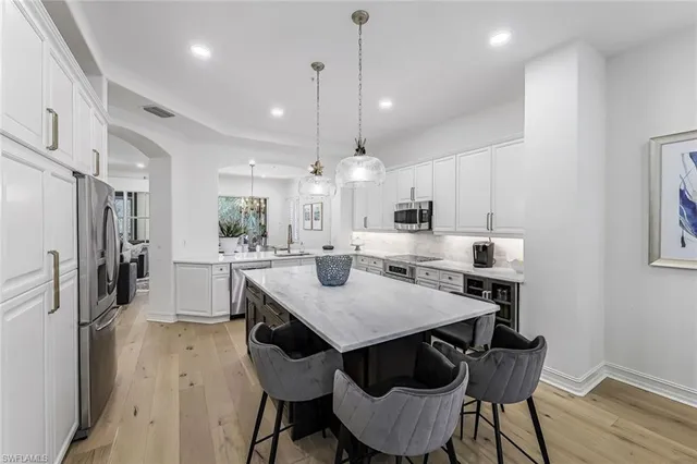 a kitchen with granite countertop a table chairs stainless steel appliances and wooden floor