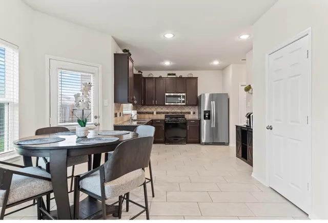 a kitchen with stainless steel appliances kitchen island granite countertop a table chairs microwave and cabinets