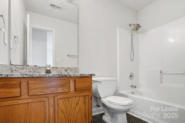 a bathroom with a granite countertop toilet sink and mirror