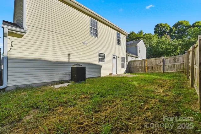a view of backyard with barbeque grill and wooden fence