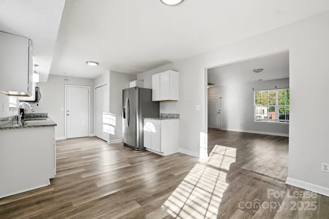 a view of a kitchen with a refrigerator a stove top oven and a wooden floor