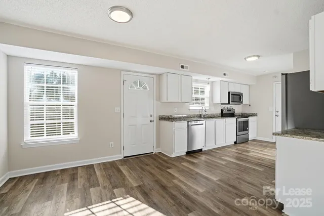 a kitchen with granite countertop a stove a sink dishwasher and a refrigerator with wooden floor