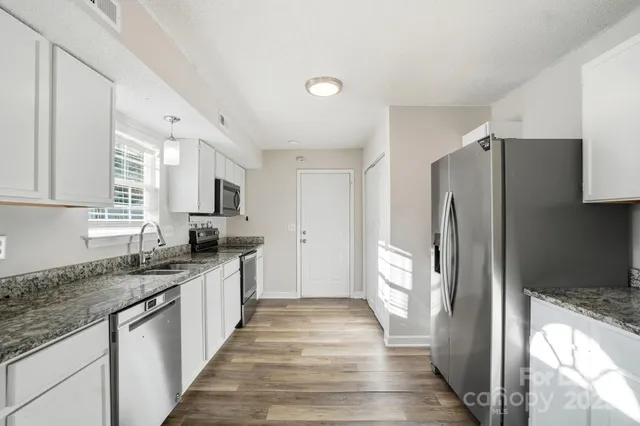 a large kitchen with stainless steel appliances granite countertop a refrigerator and a sink