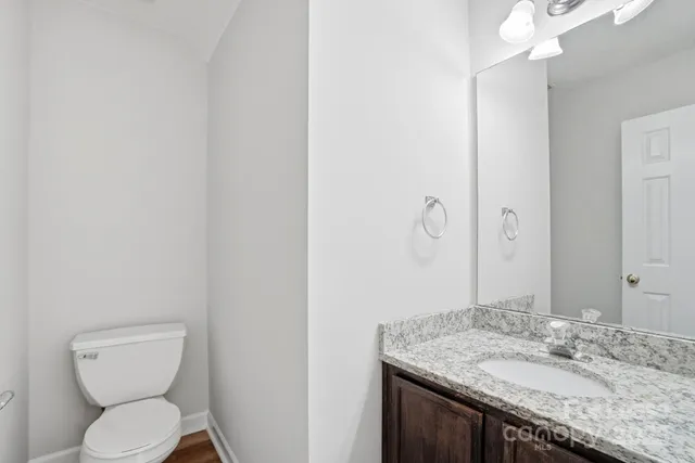 a bathroom with a granite countertop sink a toilet and a mirror