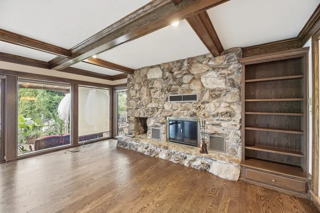 a view of wooden floor fire place and windows in an empty room
