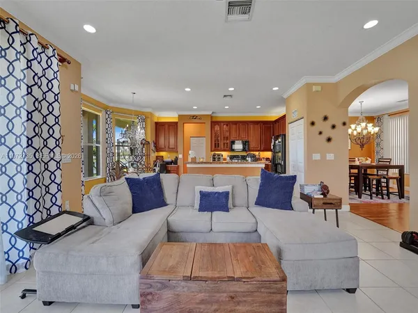 a living room with furniture kitchen view and a large window