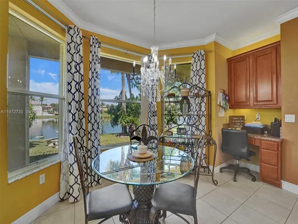 a dining hall with stainless steel appliances granite countertop a refrigerator oven a sink with island and chairs in it