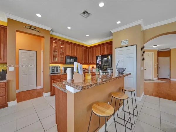 a kitchen with stainless steel appliances granite countertop a refrigerator a sink dishwasher a dining table and chairs with wooden floor