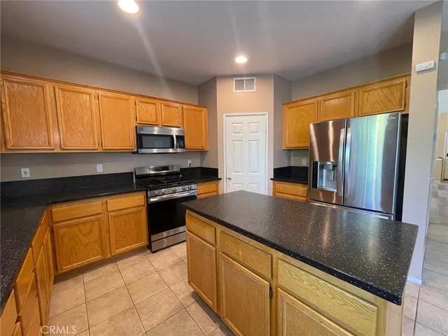 a kitchen with granite countertop a refrigerator stove top oven microwave and cabinets
