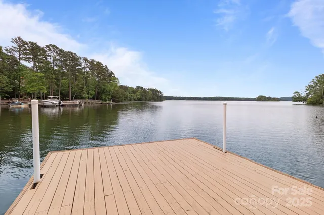 a view of wooden deck and lake with trees in the background