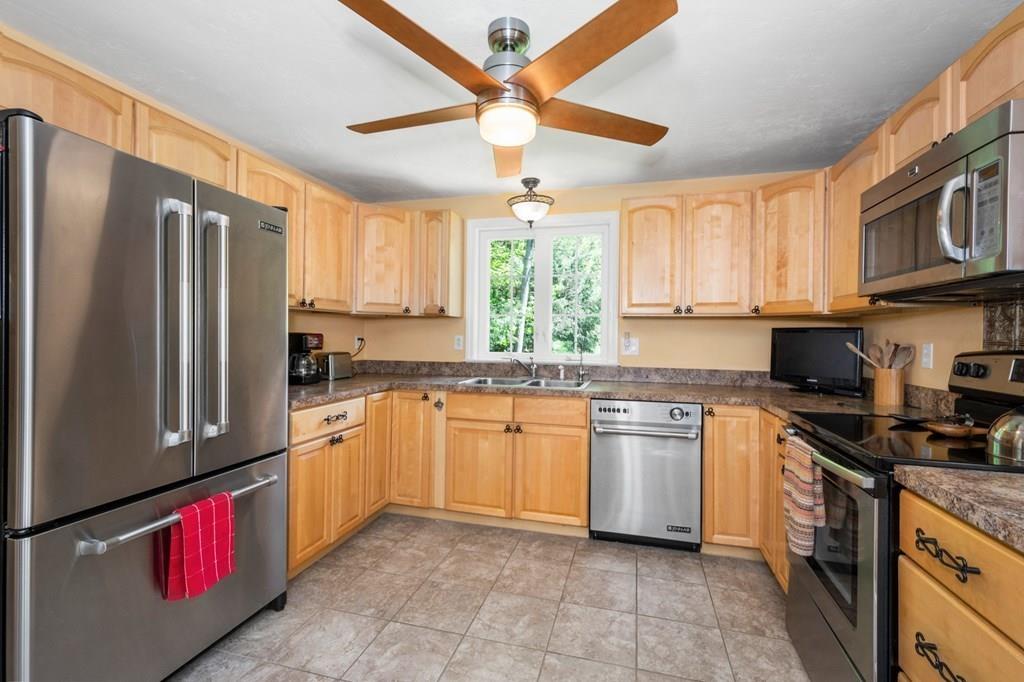 96 Sturbridge Road Holland, MA 01521 - Photo 8 of 25 a kitchen with stainless steel appliances granite countertop a refrigerator a sink dishwasher a stove top oven a dining table and chairs with wooden floor