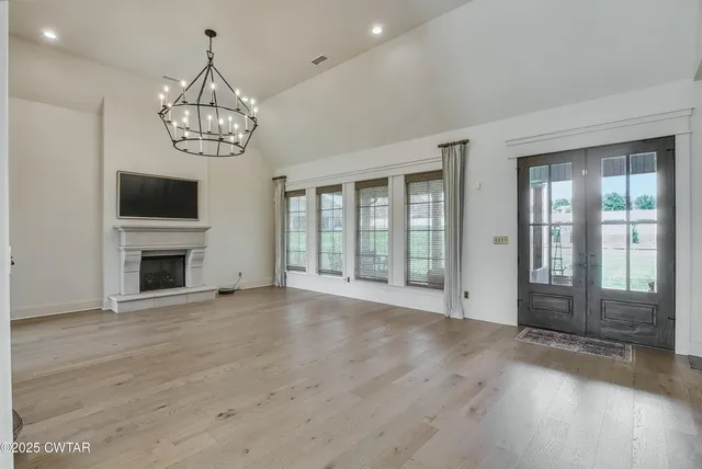 a view of a livingroom with a fireplace wooden floor and chandelier