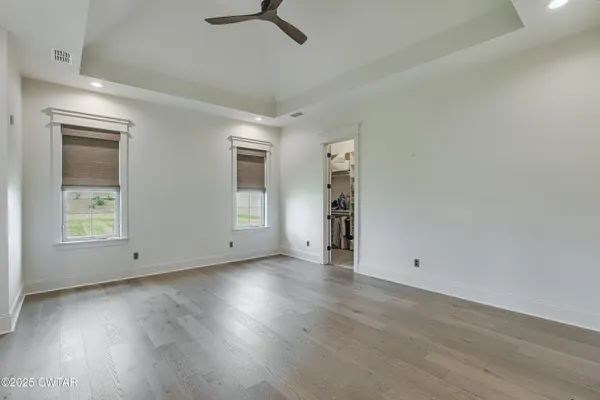 an empty room with wooden floor cabinet and windows