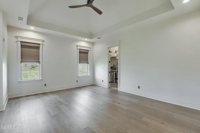 an empty room with wooden floor cabinet and windows