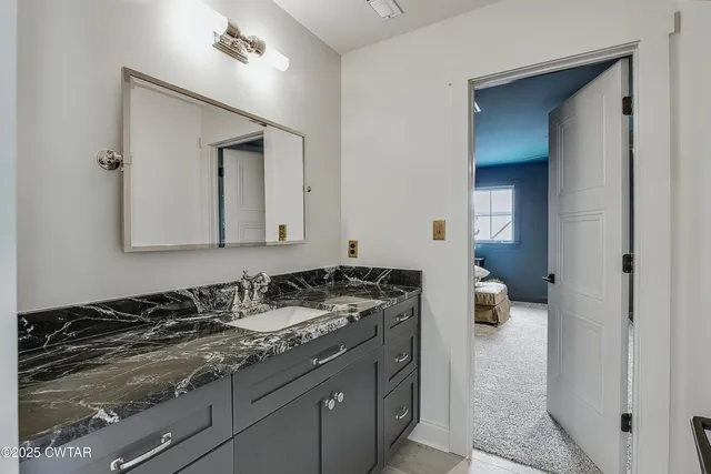 a en suite bathroom with a granite countertop sink and a mirror