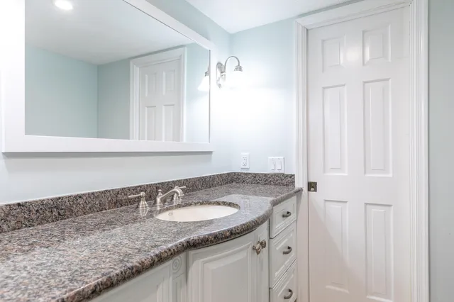 a bathroom with a granite countertop sink and a mirror