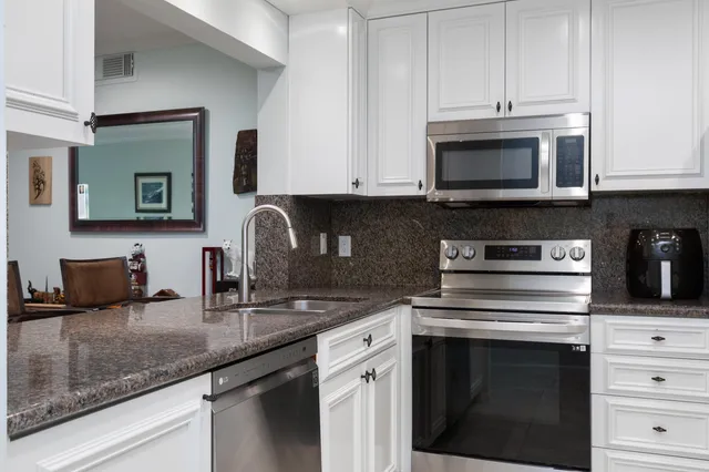 a kitchen with granite countertop white cabinets and black appliances
