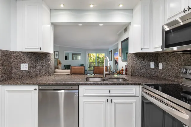 a kitchen with granite countertop a sink stainless steel appliances and cabinets