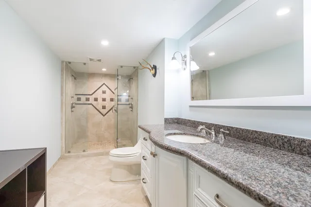a spacious bathroom with a granite countertop sink a toilet and a mirror