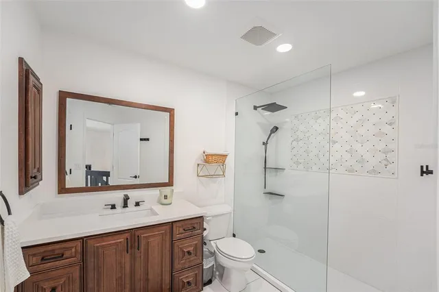 a bathroom with a toilet a sink a glass door a shower and a mirror