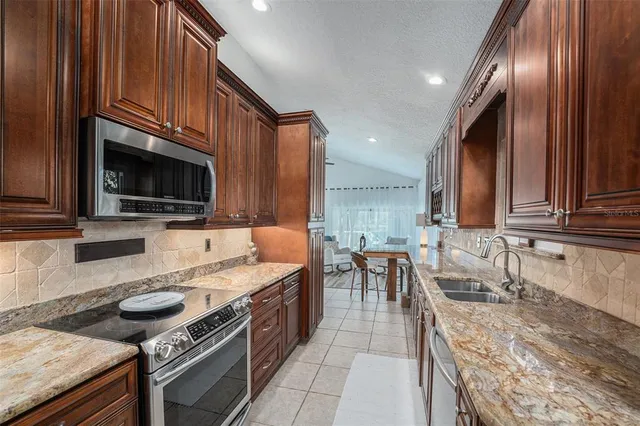 a kitchen with stainless steel appliances granite countertop a stove a sink and a microwave