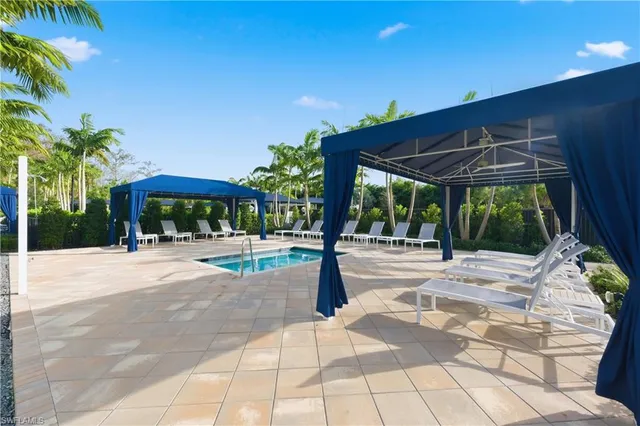 a view of a patio with a table and chairs under an umbrella with palm trees