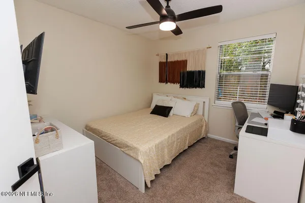 a bedroom with a bed a flat screen tv and a window