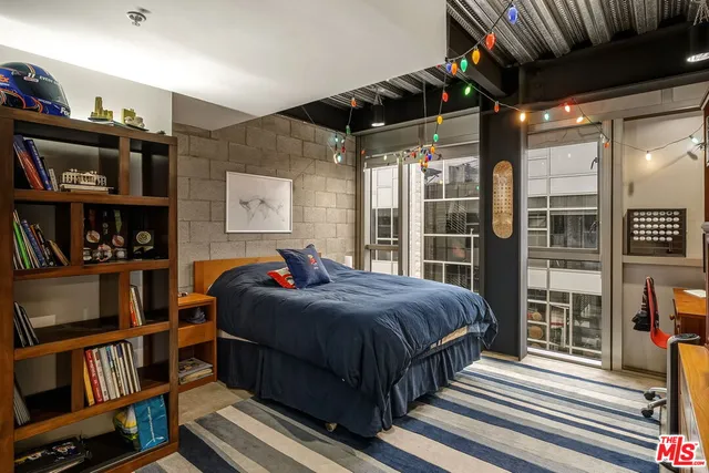 a bedroom with a bed wooden floor and book shelf
