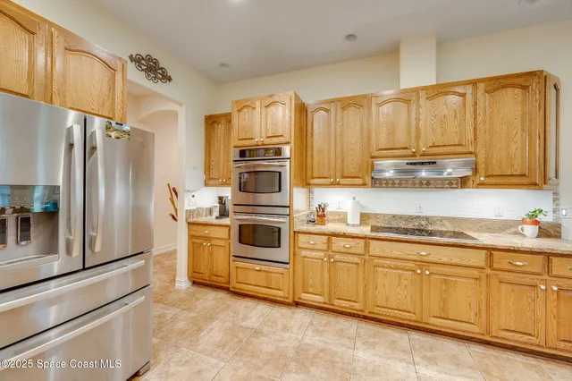 a large kitchen with granite countertop lots of white cabinets and stainless steel appliances