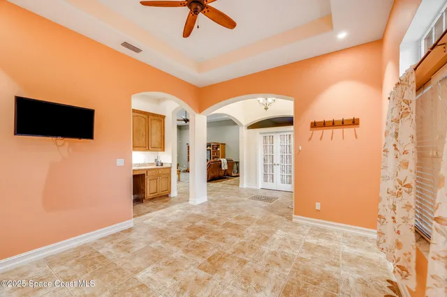 a view of a livingroom with a fireplace a ceiling fan and front door
