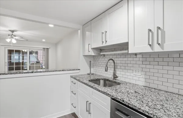 a kitchen with stainless steel appliances granite countertop a refrigerator a sink and white cabinets