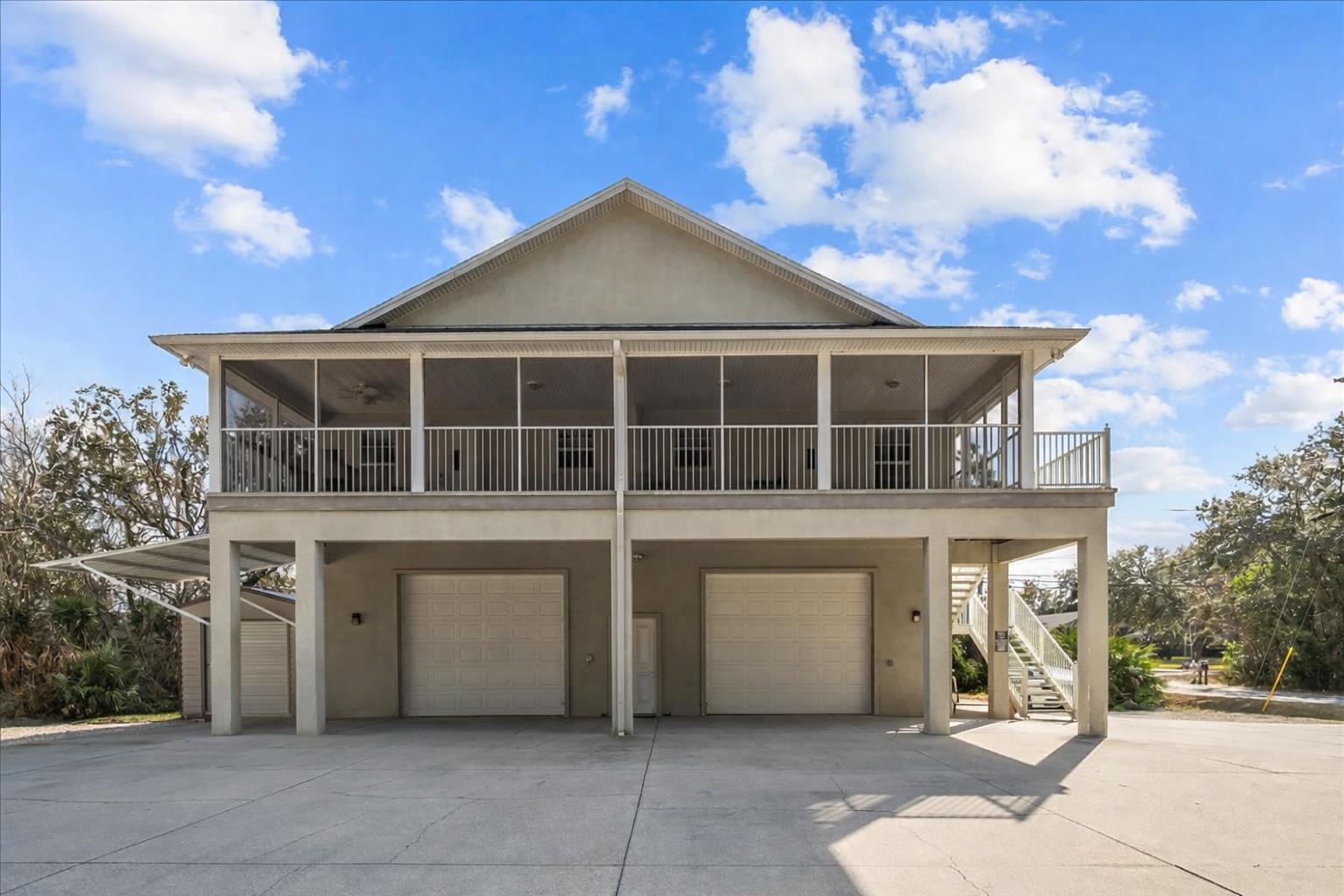 View of front of property featuring stucco siding, a garage, concrete driveway, and a deck