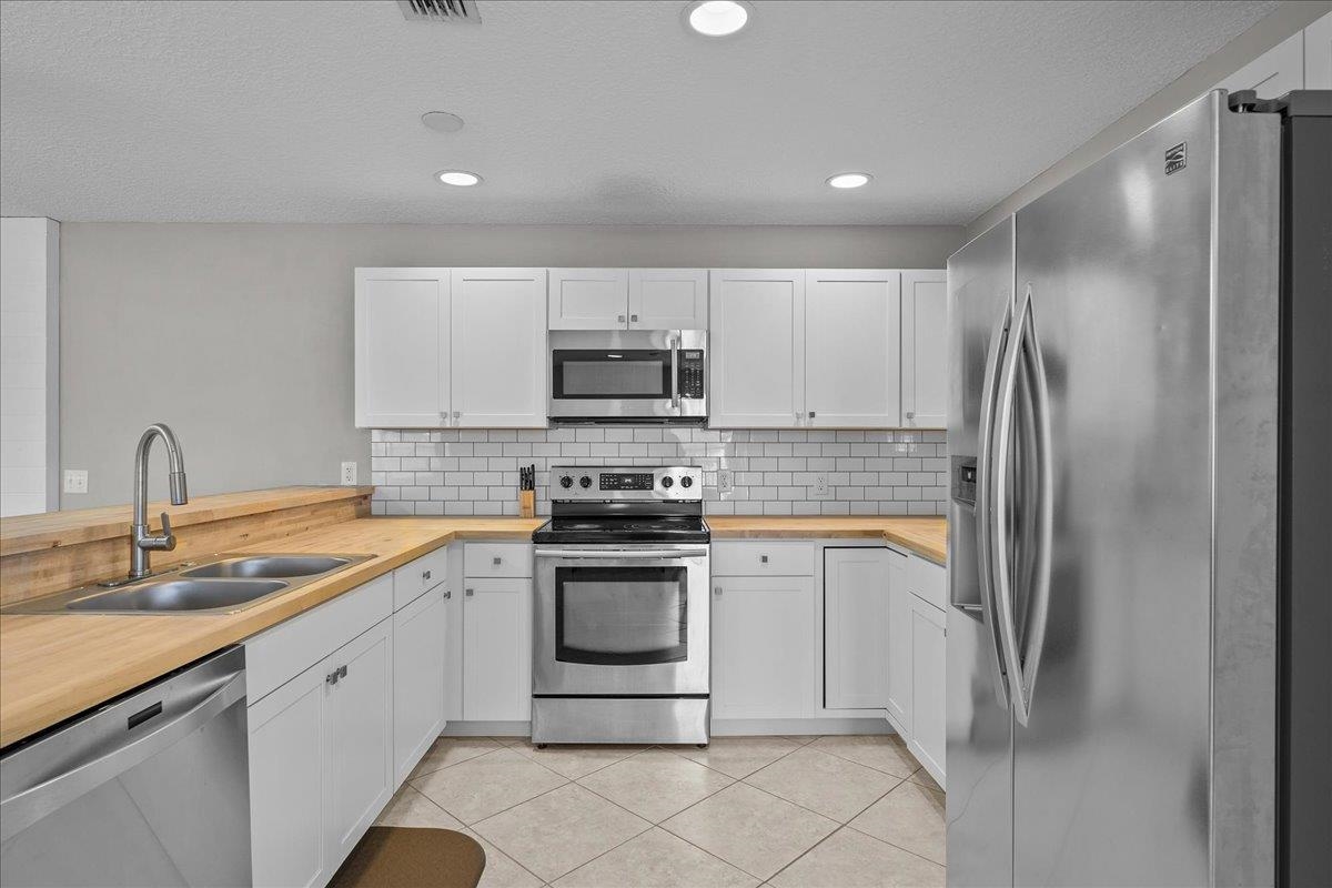 736-8 Kings Estate Road St. Augustine, FL 32086 - Photo 24 of 40 Kitchen with stainless steel appliances, white cabinetry, light tile patterned floors, recessed lighting, and backsplash