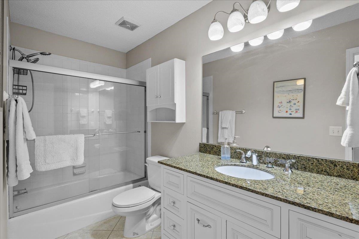 736-8 Kings Estate Road St. Augustine, FL 32086 - Photo 25 of 40 Bathroom with bath / shower combo with glass door, vanity, light tile patterned flooring, and a textured ceiling